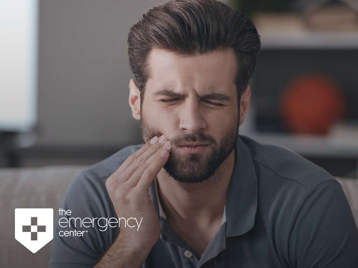 A man appears to be in discomfort, holding his cheek and closing his eyes, possibly indicating a tooth emergency or dental pain
