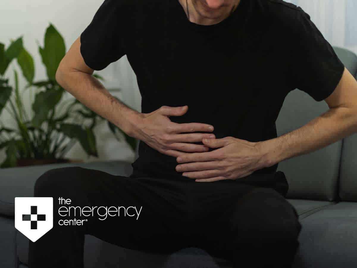 Man seated on a couch, clutching his stomach in discomfort, indicative of symptoms of acid reflux